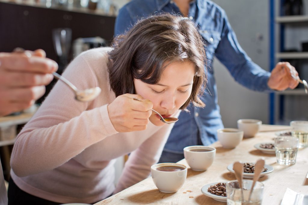 Coffee tasters sipping coffee with spoon